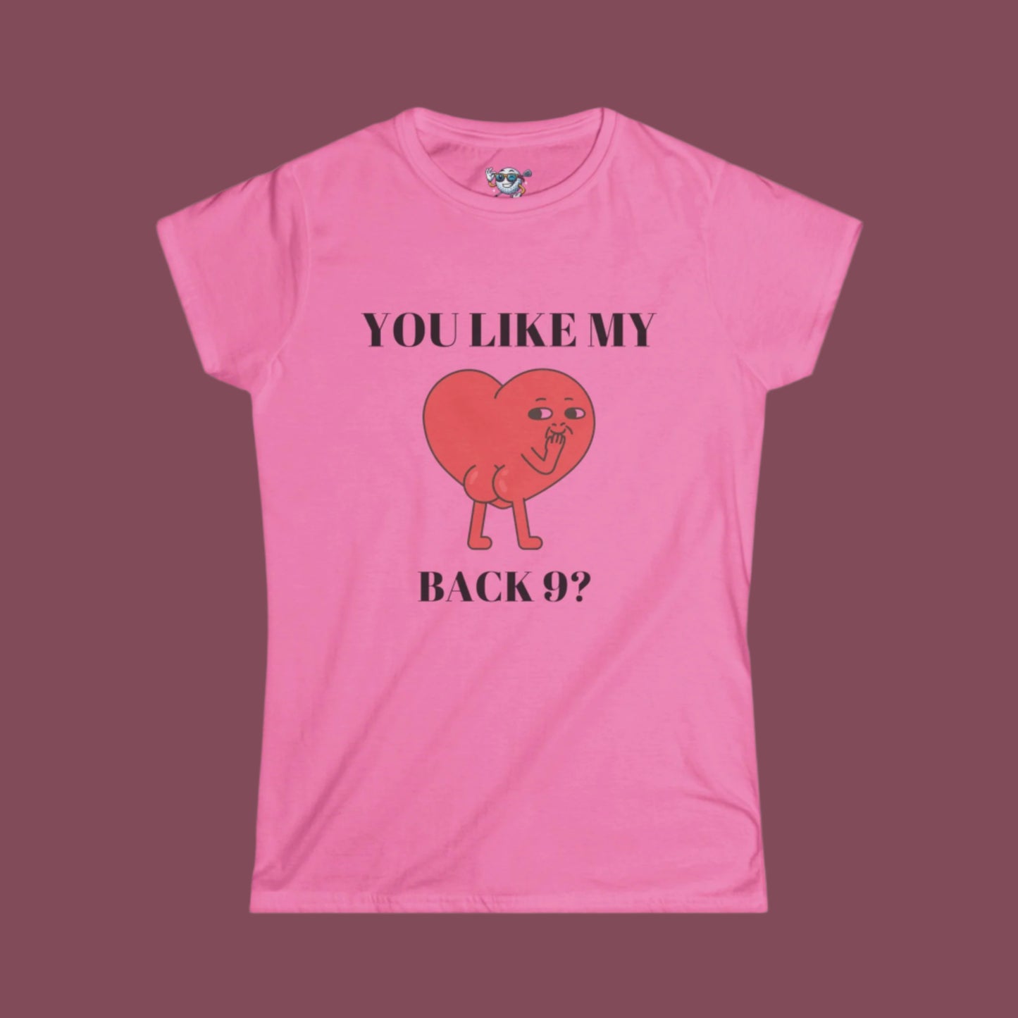 Pink Women's shirt with a heart with a face and you can see it's backside. Above the design it says. "You Like My" and under the design "Back 9?" with dark pink background